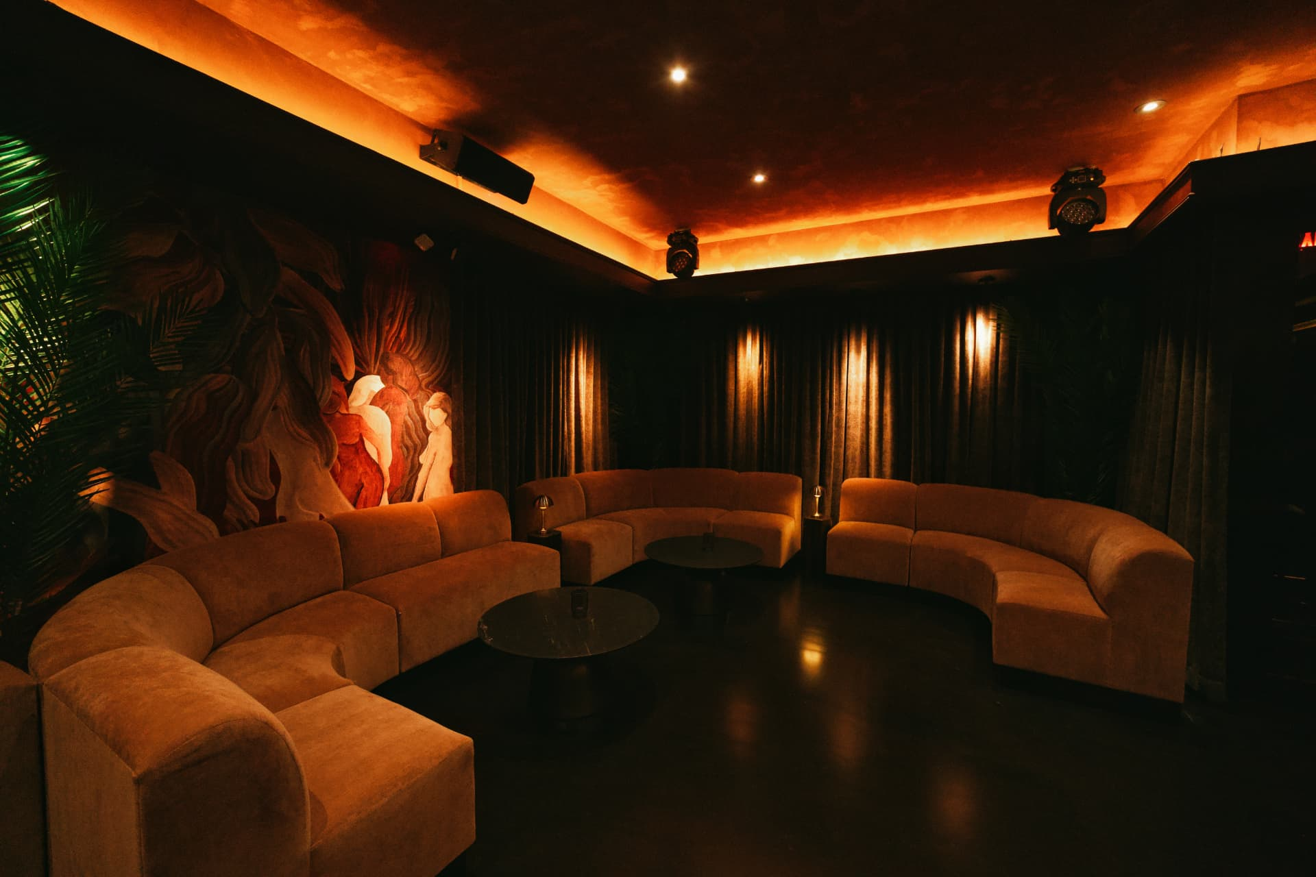 Curved velvet lounge beneath a glowing amber ceiling