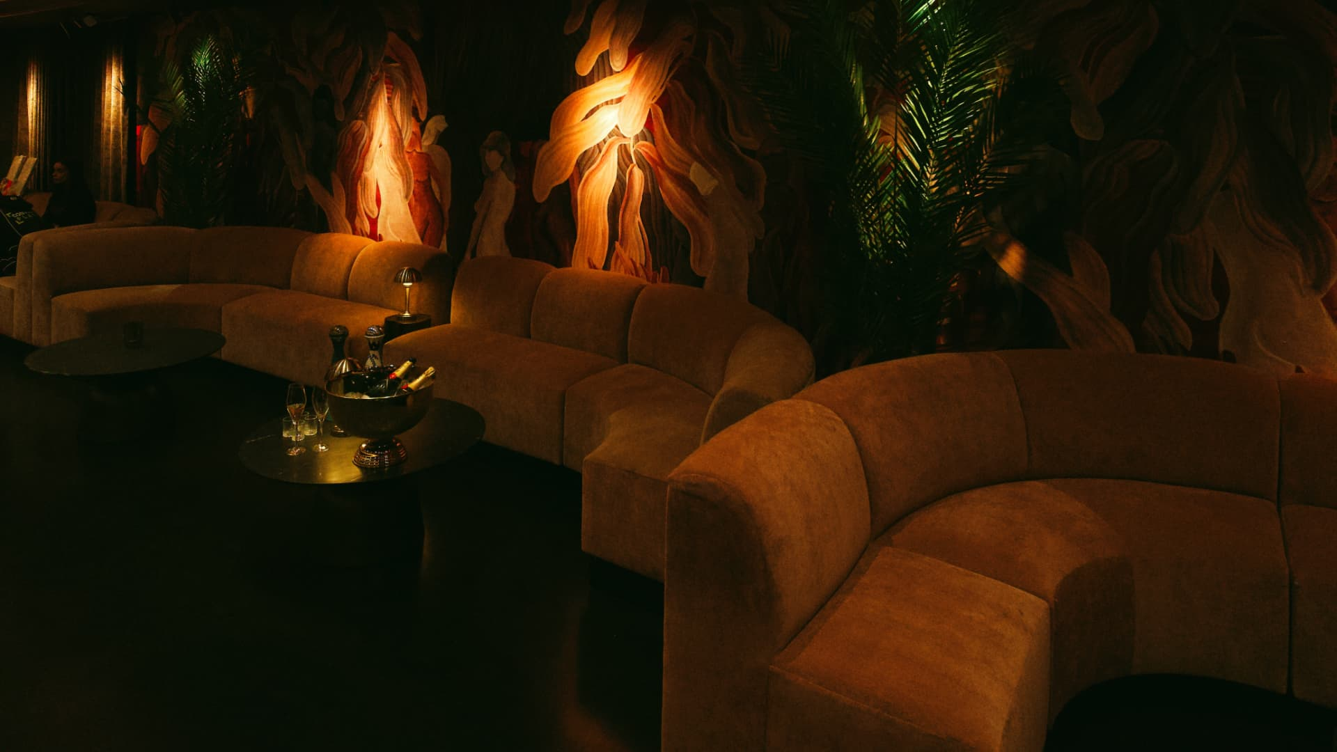 Velvet banquettes before a painted mural in candlelight